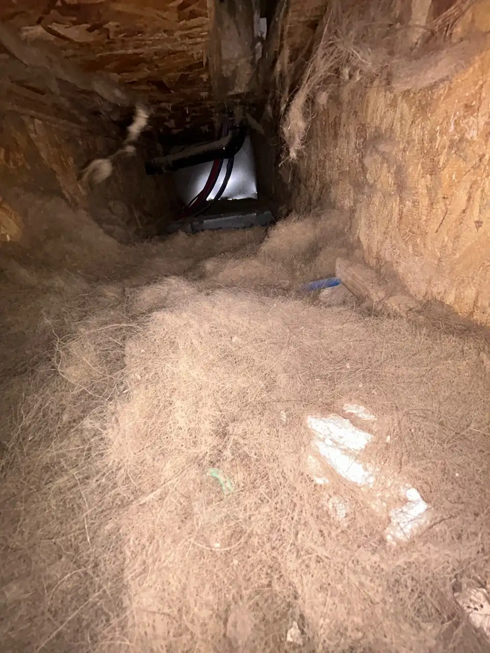 Dust and debris packed along a main duct trunk line before cleaning